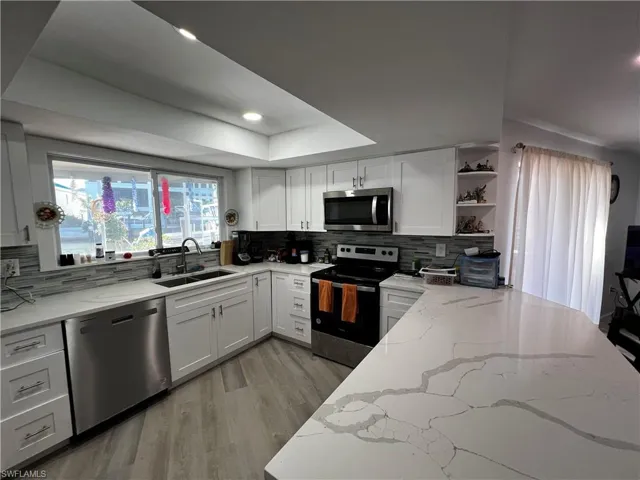 Kitchen featuring appliances with stainless steel finishes, sink, and light stone counters