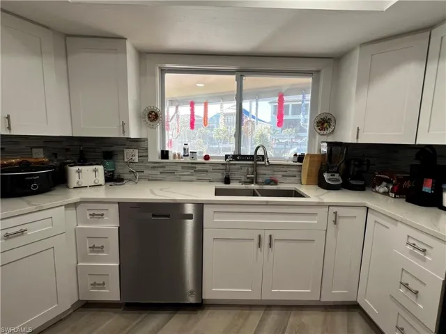 Kitchen with sink, dishwashing machine, decorative backsplash, light stone counters, and a picture window with water views