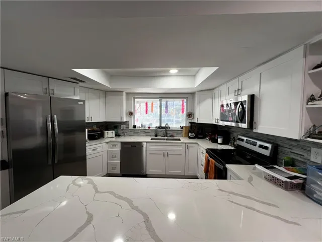 Kitchen with sink, a raised ceiling, appliances with stainless steel finishes