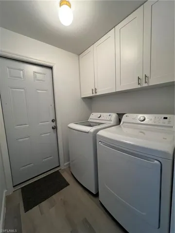 In-home Laundry room with cabinets, separate washer and dryer, and separate exit to the garage