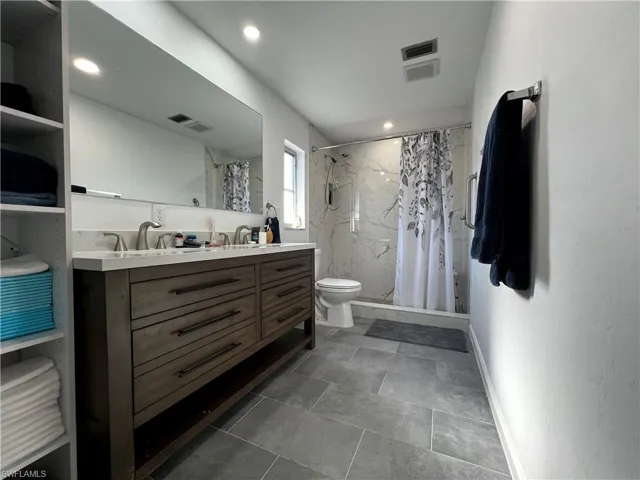 Master Bathroom with double-sink vanity, a shower with curtain, and toilet