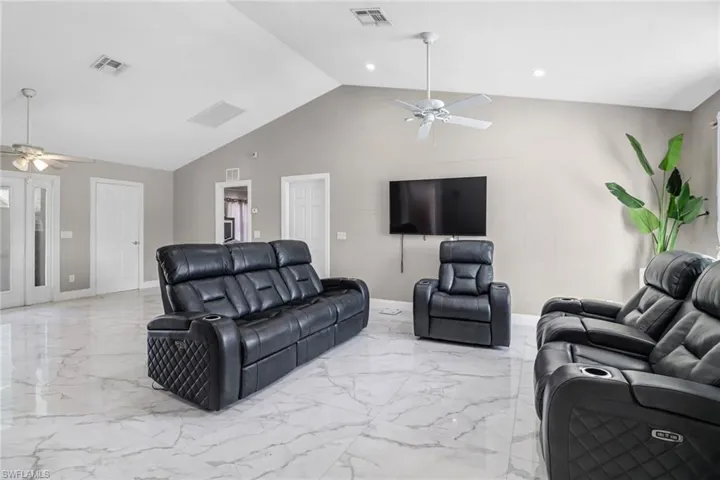 Tiled living room featuring high vaulted ceiling and ceiling fan