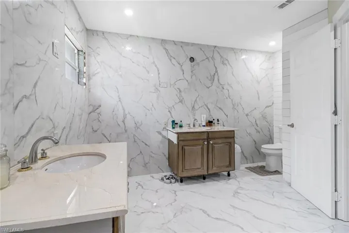 Bathroom with tile floors, tile walls, toilet, and vanity