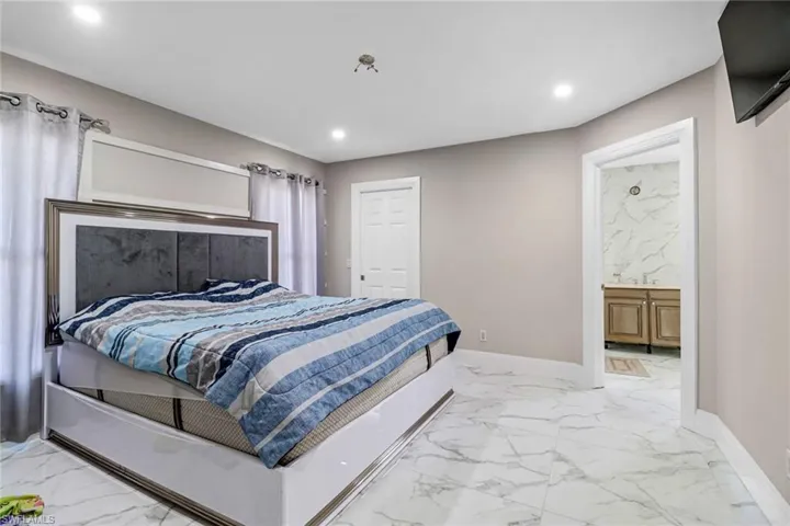 Bedroom featuring light tile flooring and ensuite bath