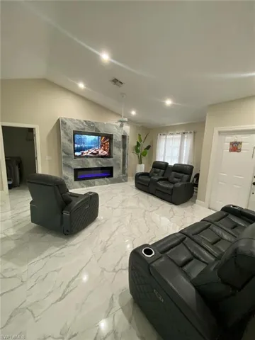 Tiled living room with a fireplace, ceiling fan, and vaulted ceiling