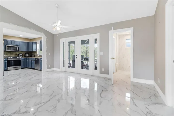 Unfurnished living room featuring ceiling fan, light tile flooring, and lofted ceiling