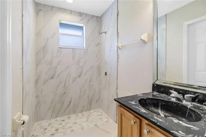 Bathroom featuring a tile shower and large vanity