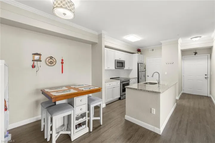 Kitchen featuring light stone counters, appliances with stainless steel finishes, and white cabinetry.