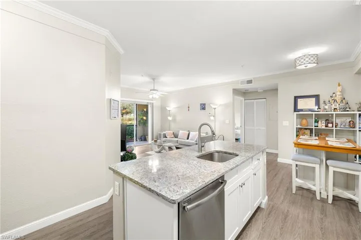 Kitchen featuring white cabinets, an island with sink, light wood-type flooring, dishwasher, and sink