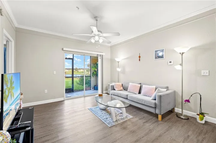 Spacious living room with crown molding, luxury vinyl flooring with views of the pond.