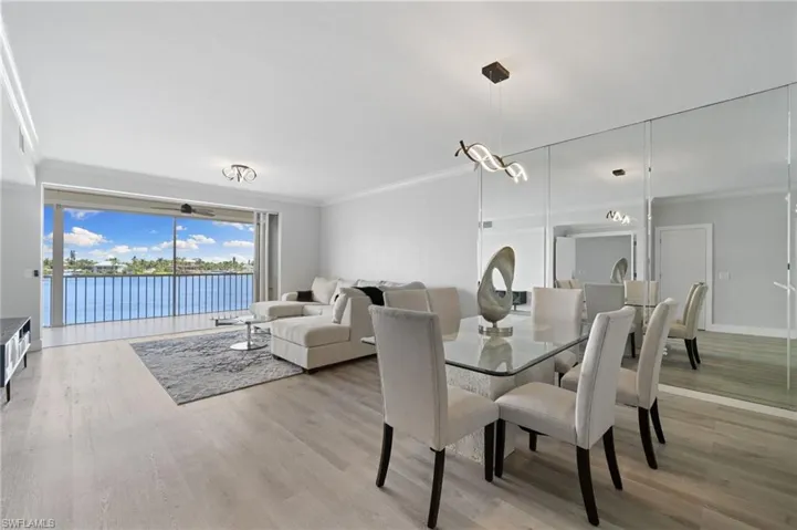 Dining space featuring ornamental molding, a water view, and light wood finished floors