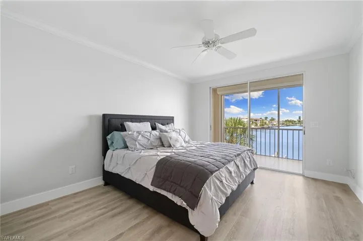 Bedroom featuring a water view, crown molding, access to exterior, light wood-style floors, and ceiling fan
