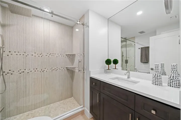 Bathroom with a shower stall, vanity, and recessed lighting
