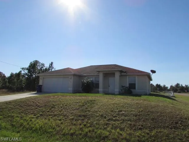 View of front facade featuring concrete driveway, a front yard, a garage, and stucco siding