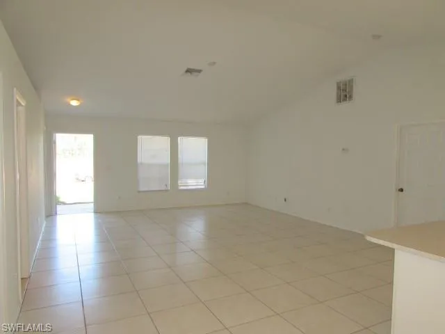 Spare room with light tile patterned floors and vaulted ceiling