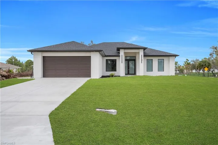 Prairie-style home with stucco siding, a garage, concrete driveway, and a shingled roof