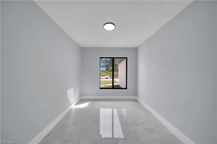 Spare room featuring light marble finish floors and baseboards