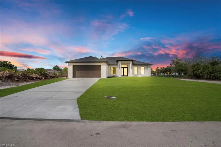 Prairie-style home with a lawn, concrete driveway, a garage, and stucco siding
