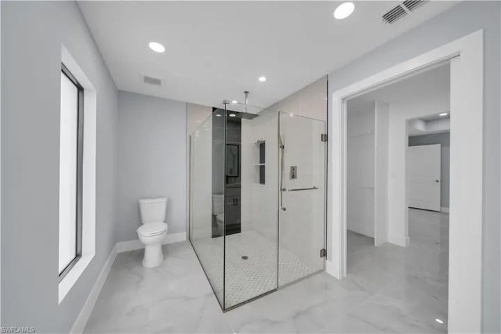 Bathroom with light marble finish floors, a stall shower, and recessed lighting