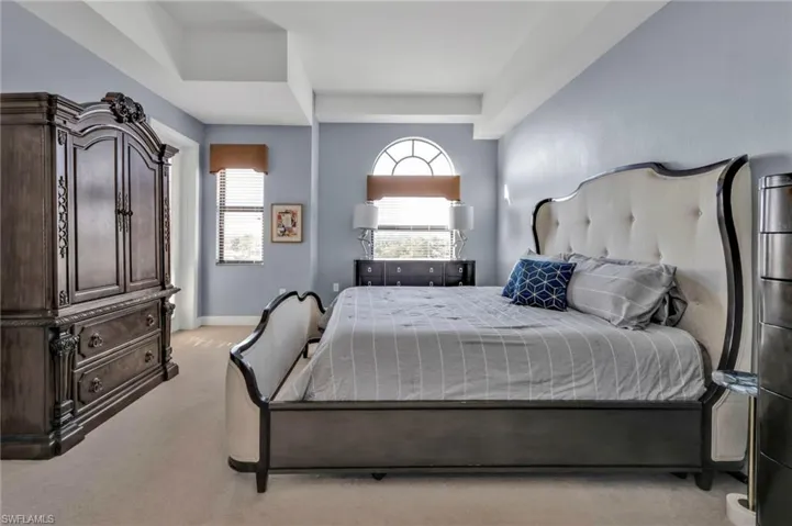 Carpeted bedroom featuring baseboards and a tray ceiling