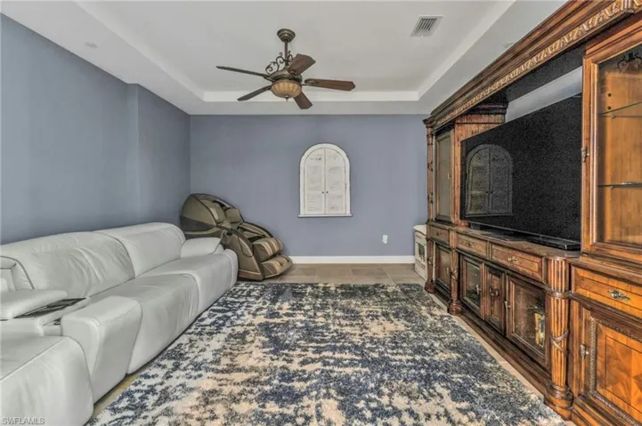 Living area featuring a raised ceiling, visible vents, ceiling fan, tile patterned flooring, and baseboards