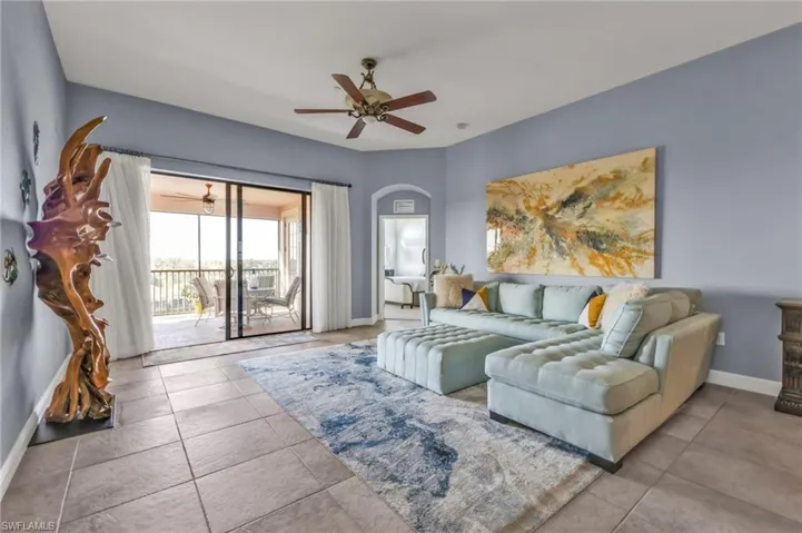 Living area with baseboards, arched walkways, a ceiling fan, and tile patterned floors
