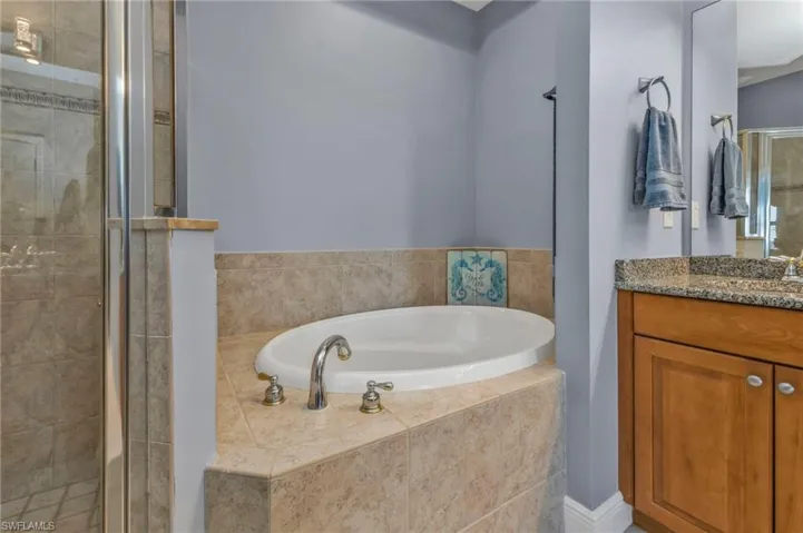 Full bathroom featuring a garden tub, a shower stall, and vanity