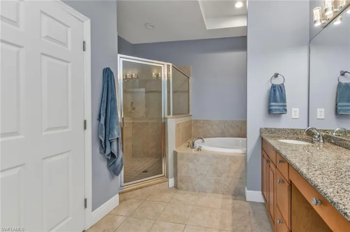 Full bathroom featuring a garden tub, a shower stall, tile patterned floors, and vanity
