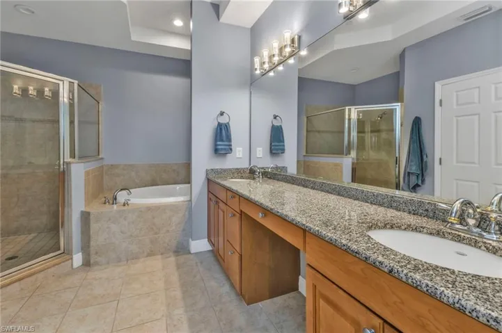 Full bath featuring a garden tub, tile patterned flooring, a sink, and a stall shower