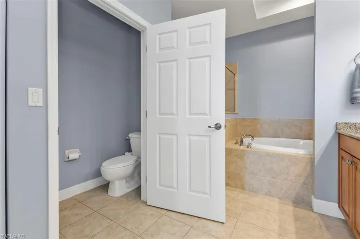 Full bath featuring toilet, a garden tub, tile patterned floors, and vanity