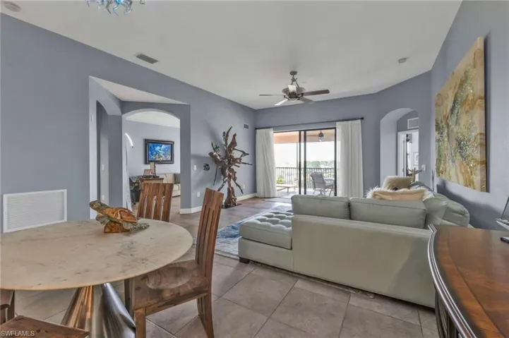 Living area featuring ceiling fan, visible vents, arched walkways, and baseboards