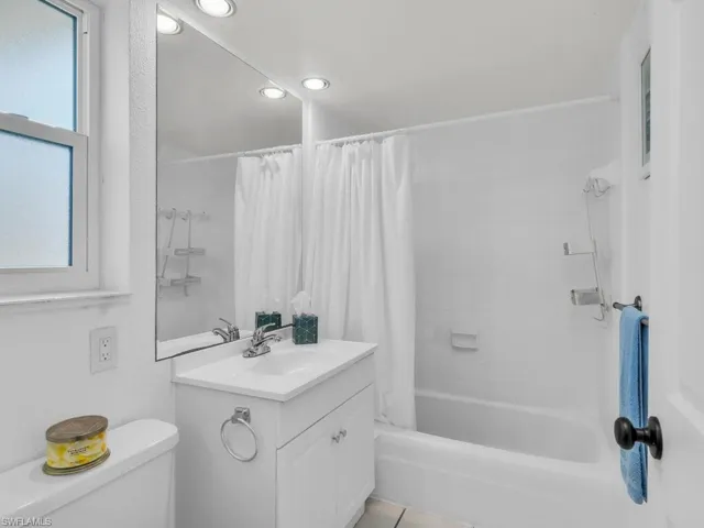 Bathroom featuring shower / tub combo with curtain, plenty of natural light, vanity, and toilet