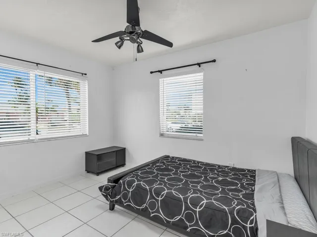 Bedroom featuring light tile patterned floors, a ceiling fan, and baseboards