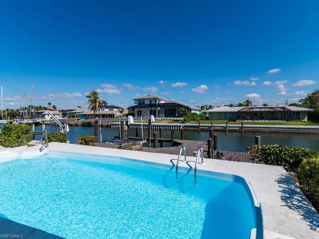 Outdoor pool featuring a dock, a water view, boat lift, and a residential view