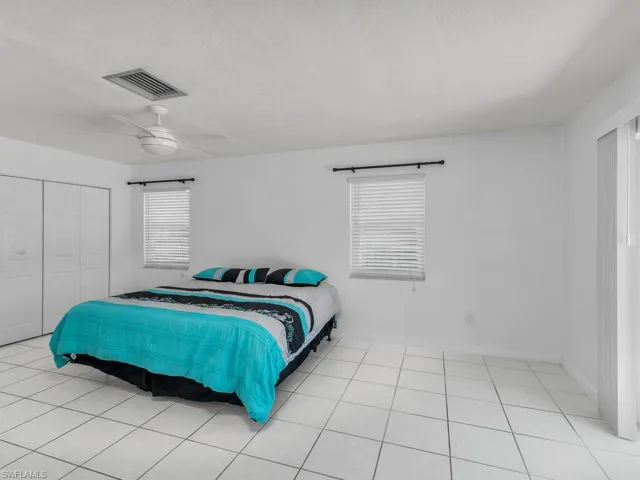 Bedroom with ceiling fan, a textured ceiling, light tile patterned flooring, visible vents, and a closet