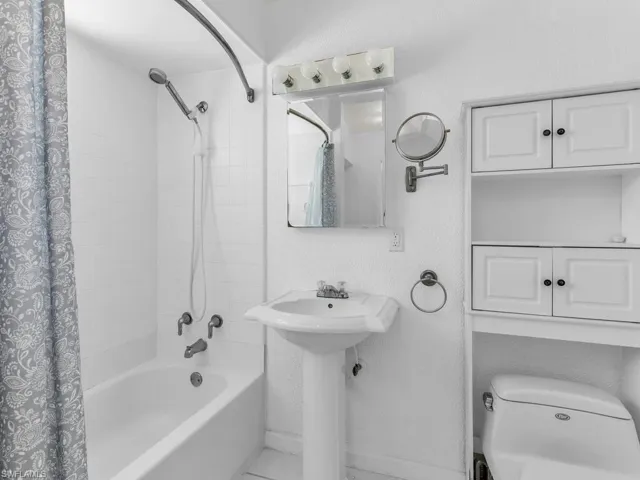 Bathroom with baseboards, toilet, and shower / bath combo with shower curtain