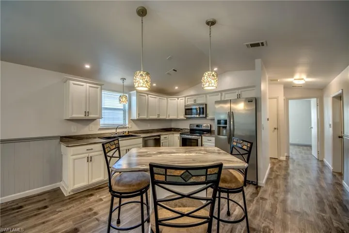 The kitchen features white cabinetry, dark countertops, and stainless steel appliances
