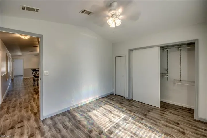This room features wood-look flooring, a ceiling fan with integrated lighting, and a closet with sliding doors and shelving