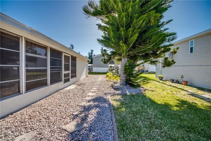 The property features an extensive side yard with a gravel pathway and stone pavers, bordered by a well-maintained lawn and a mature tree
