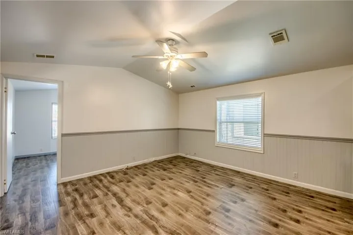 This room features wood-look flooring, a ceiling fan with integrated lighting, and a window with blinds