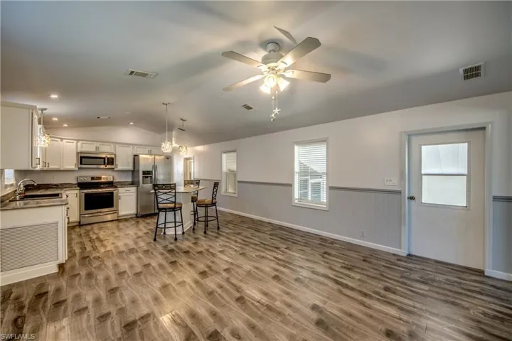 The property features an open concept kitchen and living area with wood-look flooring and a ceiling fan