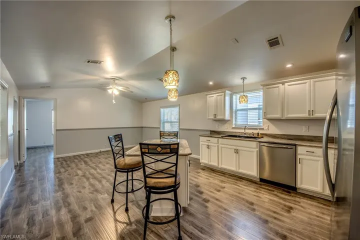 The property features an open-plan kitchen and living area with wood-style flooring, white kitchen cabinetry, and stainless steel appliances