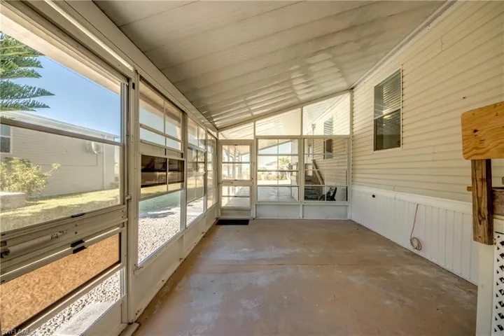 This property features an enclosed porch with a sloped ceiling and concrete flooring, offering ample natural light through its numerous windows