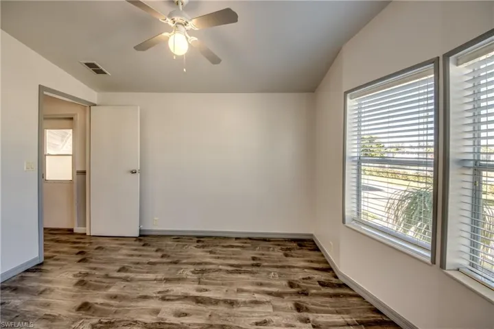 This room features durable plank flooring, a ceiling fan with integrated lighting, and white walls with gray trim