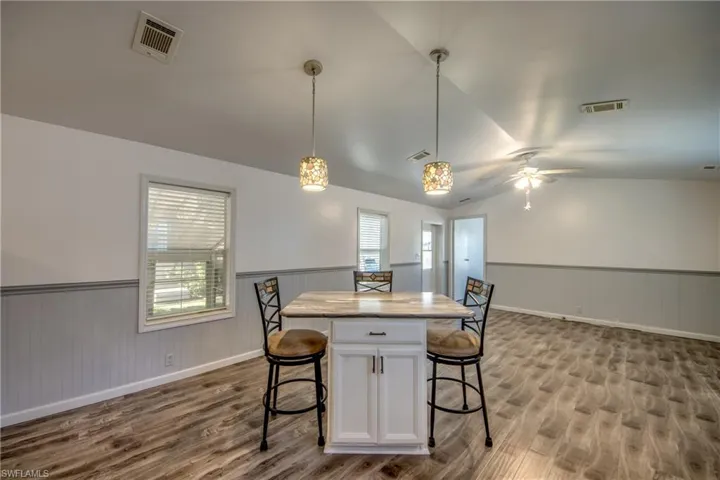 Open concept living space featuring wood-look flooring, white and gray wainscoting, and a ceiling fan