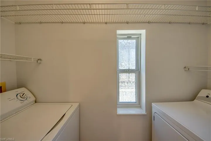 Dedicated laundry area featuring a window, wire shelving, and space for appliances