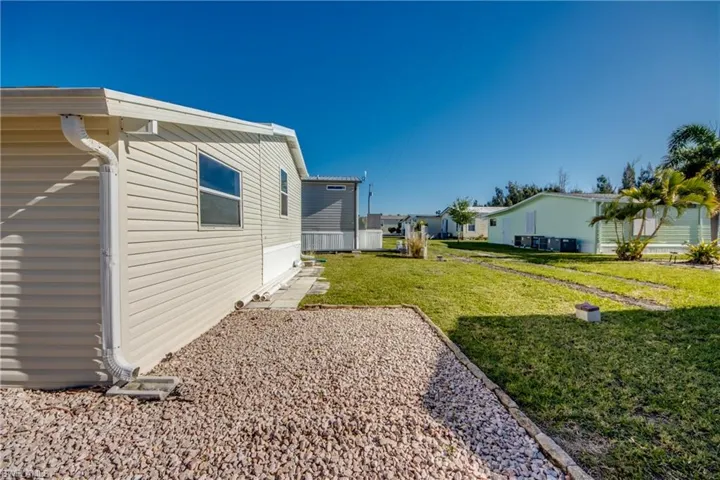The property features light-colored siding, with a gravel area alongside, and a well-maintained lawn