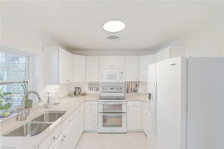 Kitchen featuring white cabinetry, white appliances, and sink