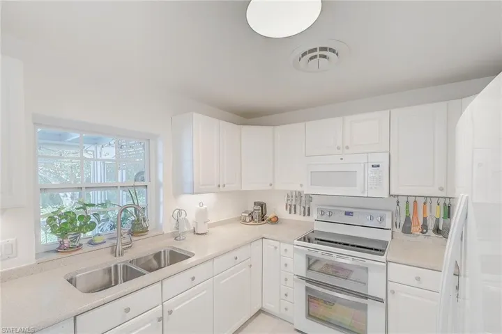 Kitchen with sink, white cabinets, and white appliances