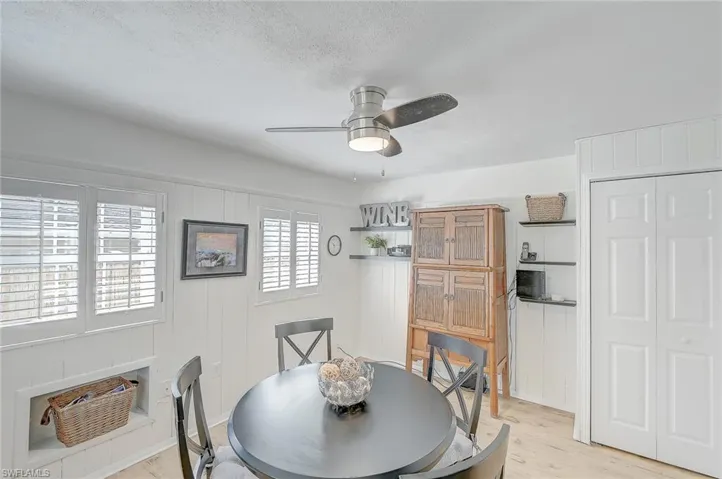 Dining space with ceiling fan, a wall mounted air conditioner, light hardwood / wood-style flooring, a textured ceiling, and wooden walls